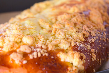 Close up of a large browned curd strudel (yeast-cake) with crumble. Cake freshly removed from the oven on a baking tray lined with paper. Shallow depth of field.