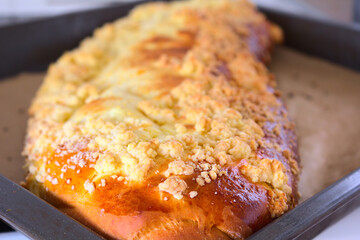 Close up of a large browned curd strudel (yeast-cake) with crumble. Cake freshly removed from the oven on a baking tray lined with paper. Shallow depth of field.