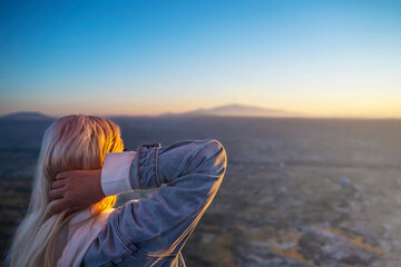 Girl from a balloon watches the sunrise over the fabulous hills of Cappadocia