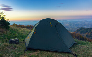 Green tourist tent against the background of an evening mountain landscape