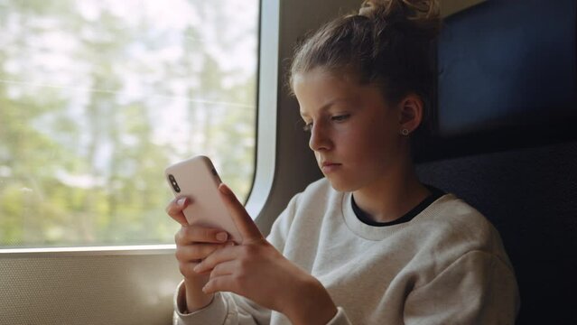 Young Girl Using Smartphone On Train Journey