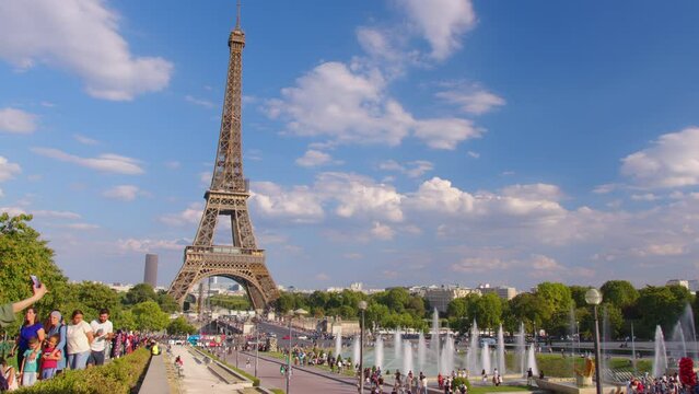 Timelapse, movement of clouds. People walk in Paris with the Eiffel Tower in the background. The most popular tourist attraction in the world. Paris, France