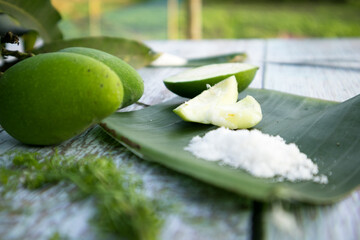 Some raw mango or kaccha aam with some ingrediants like chilli, salt, pudina and garden presly