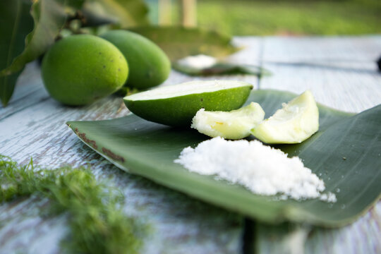 Some raw mango or kaccha aam with some ingrediants like chilli, salt, pudina and garden presly