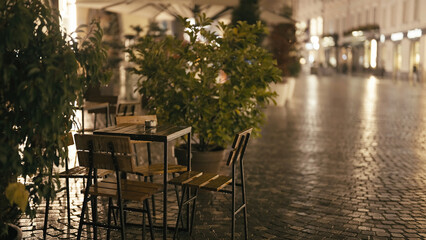 Empty coffee table and chairs in Ljubljana city at night in rain