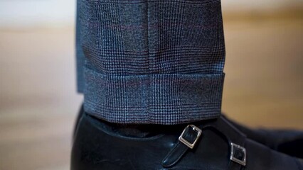 Side view close up of suit trousers cuff and patent shoes with straps.