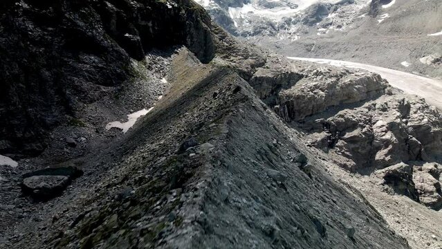 Aerial FPV like shot moving forward tracing the shape of the mountain with a glacier in the background in Zinal, Switzerland