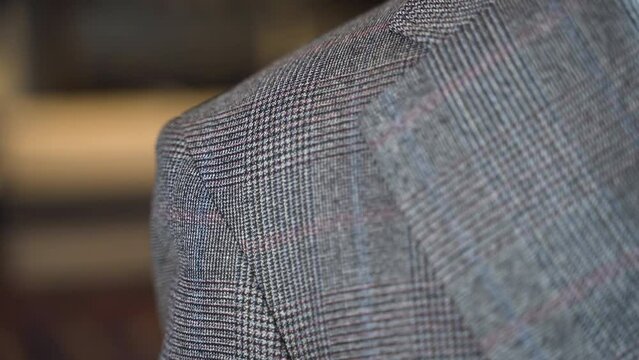 Trying thickness of grey tweed suit jacket shoulder pad, close up.