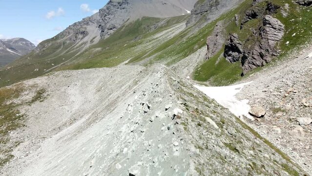 Aerial FPV like shot moving forward tracing the shape of the mountain with many hikers walking around in Zinal, Switzerland