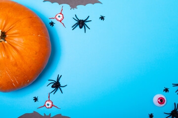 Multiple scary eyes, spider, bat toys and pumpkin with copy space on blue background - Powered by Adobe