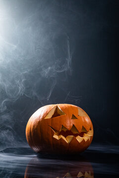Close up of carved halloween pumpkin against smoke effect on grey background