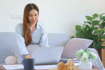 Home office concept, Businesswoman sitting on the couch to typing marketing plan report on laptop