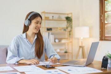 Home office concept, Businesswoman wear headphone to meeting in video call and taking notes data