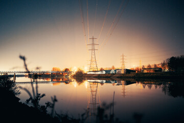 Newburn UK: 6th march 2022: Newburn Riverside at night electric pylons, rowing club and still river with warm glowing industrial light