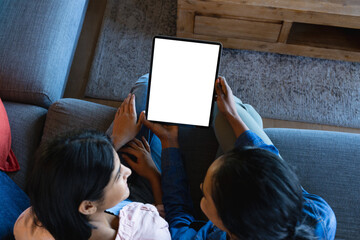 High angle view of biracial mother and daughter looking at each other while using digital tablet - Powered by Adobe