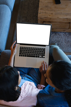 High Angle View Of Biracial Teen Daughter With Mother Using Laptop While Sitting On Sofa At Home