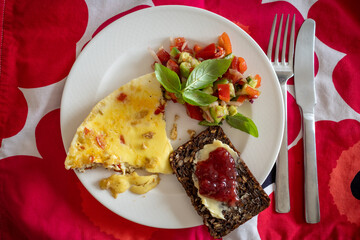 A breakfast plate with omelette, bread and jam, and salsa with basil.