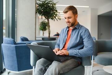 Handsome young businessman, using a laptop in the cafe.