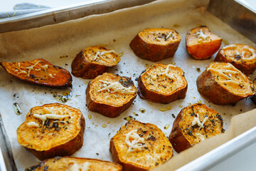Baked sweet potato on baking sheet with herbs. Vegetarian food, dinner or lunch. soft focus