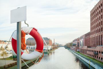 Fototapeta premium Lifebuoy on the city embankment. Coast security. For news of banner.