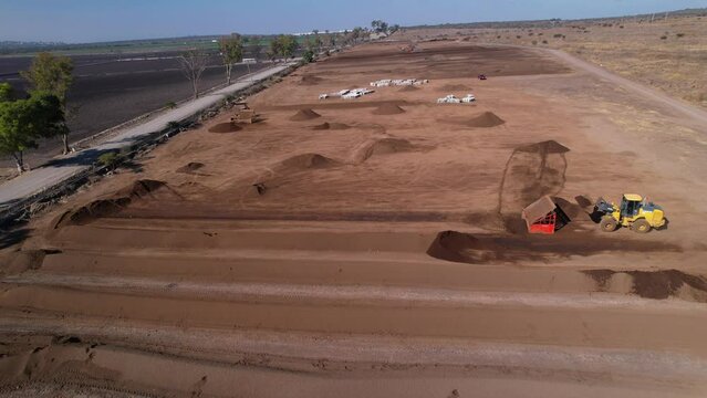 low aerial pull back of yellow tractors working on a compost farm in mexico