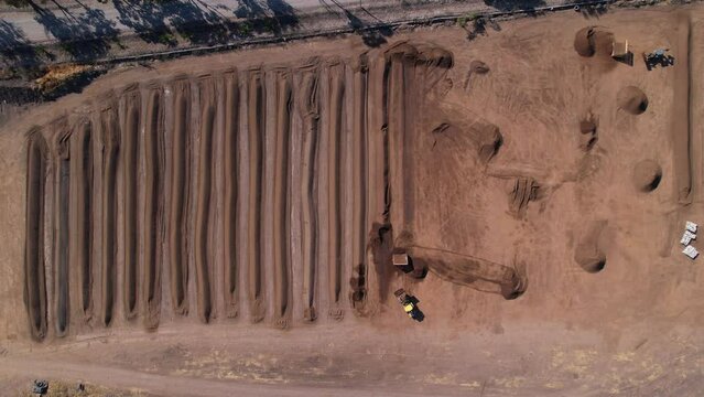 aerial of yellow tractor scooping up compost mixture on a large farm in mexico