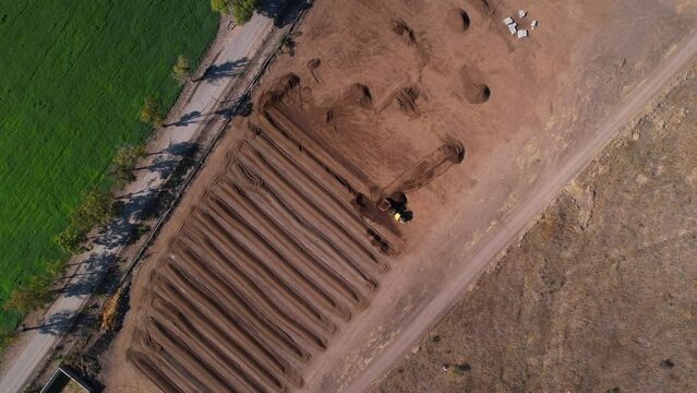 Aerial rotation of yellow tractor working with compost mixture on a farm in mexico