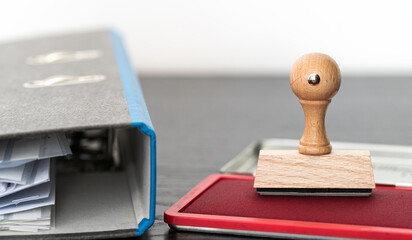 rectangular rubber stamp on ink pad on wooden desk with filing folder