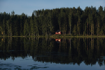 Fototapeta premium Red cottage in the middle of a forest by a lake