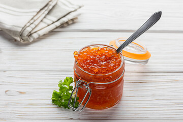 Fresh red caviar with parsley in jar and silver color spoon