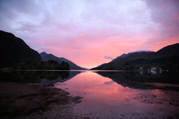 Scottish highlands sunset with pink sky, mountains and lake