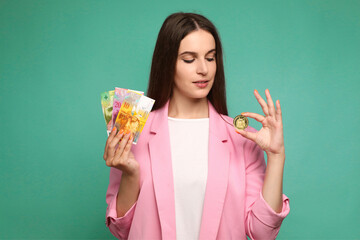 Portrait of young woman holding crypto currency and swedish krona banknotes and looking on crypto currency