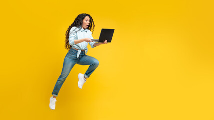 Fototapeta na wymiar Arabic Woman Holding Laptop Running In Mid Air, Yellow Background