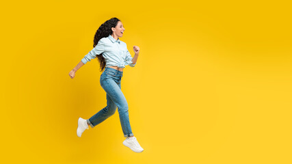 Fototapeta na wymiar Joyful Arabic Lady Running In Mid Air Over Yellow Background