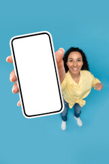 Obraz premium Above view of young woman pointing at mobile phone with blank screen, advertising website, offering space for ad mockup