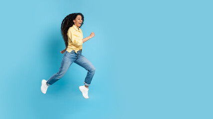 Fototapeta na wymiar Cheerful Middle Eastern Woman Running In Mid Air, Blue Background