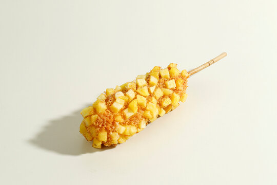 Delicious Crunchy Korean Style Chunky Potato Corn Dogs with Batter and Fried Potatoes. Isolated on Cream Background