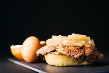 Doble smashburger with coocked onion and a boiled egg over a black background