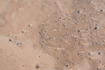 Top view on different color pebbles in the wet sand making abstract pattern
