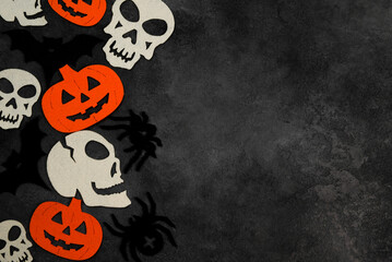 Halloween background with bats,spiders,pumpkins and skulls on dark concrete background.