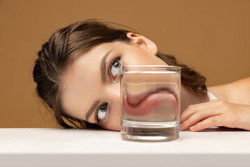 Modern art photography. Beautiful girl's face through glass of water. Object distortion, optical...
