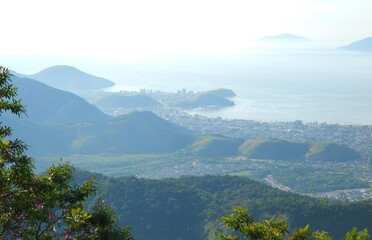 Mountains, a lot of green, the sea in the background and below the city of Caraguatatuba, São Paulo, Brazil.