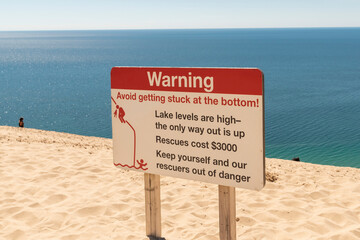 A warning sign urges caution on the steep slopes of Sleeping Bear Dunes National Seashore in Michigan.