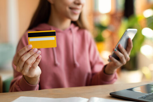 Smart teen girl student pay money with credit card and smartphone, shopping online while sitting at home