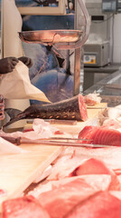 Vertical view of tuna fish tail cut on a cutting board with unrecognizable fisherman hand