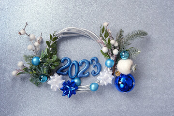 New Year 2023 concept. festive Christmas wreath, 2023 numbers, balls on abstract silver glittering...