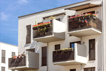 Balcony Flowers. Modern Facade Building with Decorated Balconies against blue sky. 