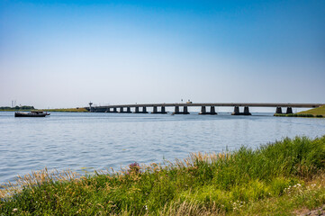 Fototapeta na wymiar Nagele, Flevoland, The Netherlands - Bridge over the Ketel lake with the green polder and ships