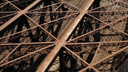 Iron works on railroad bridge casting shadows on track below