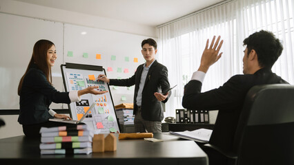 Male entrepreneur smiling while delivering a presentation to team in office boardroom. Businesswoman having meeting with colleagues with coworkers in office.